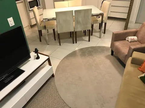 Apartamento Ingleses: a mesa vista da sala, na posição enviesada, com o tapete redondo em primeiro plano