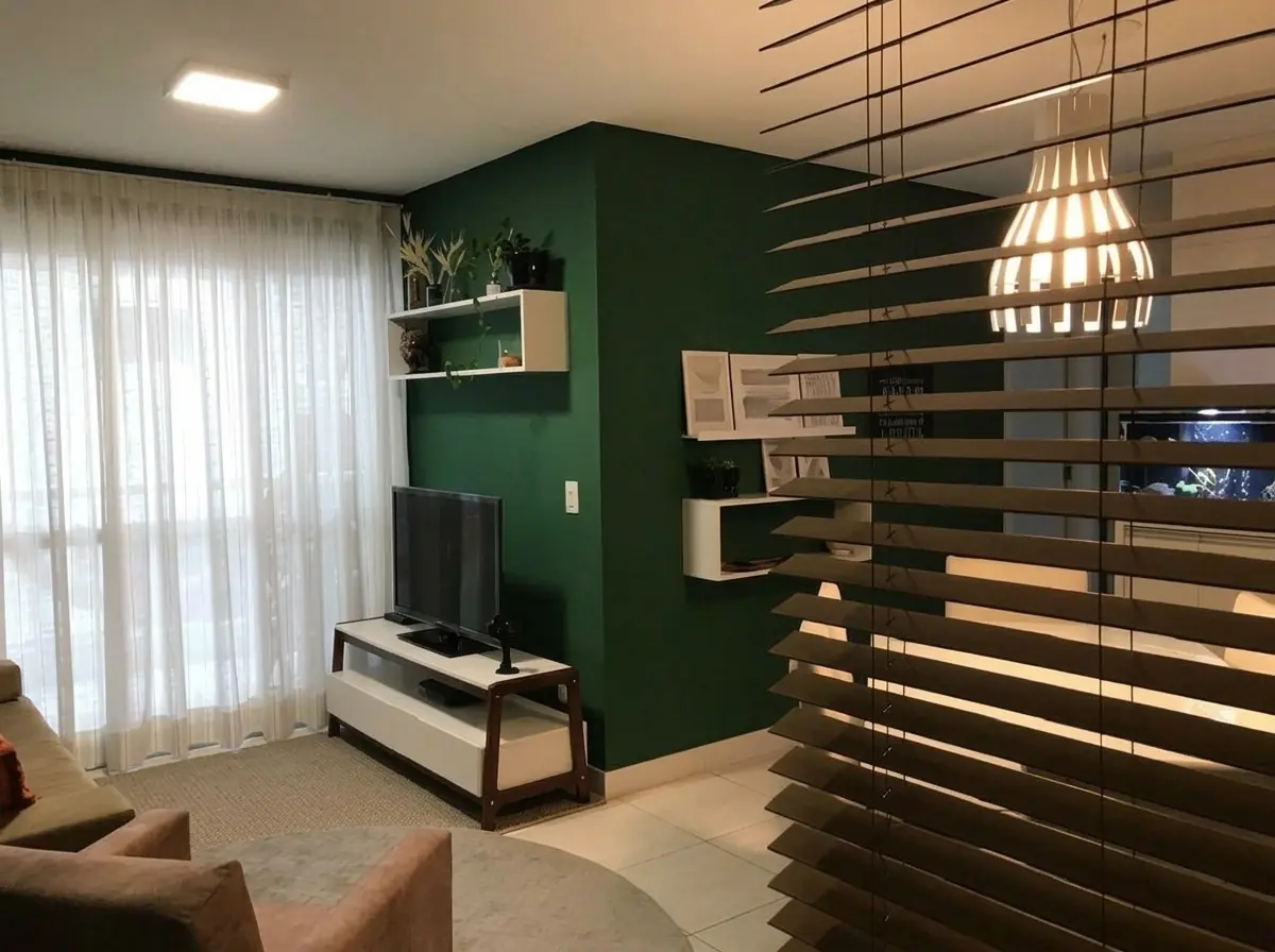 Apartamento Ingleses: a persiana de madeira na entrada, em primeiro plano, e a sala com a parede verde ao fundo