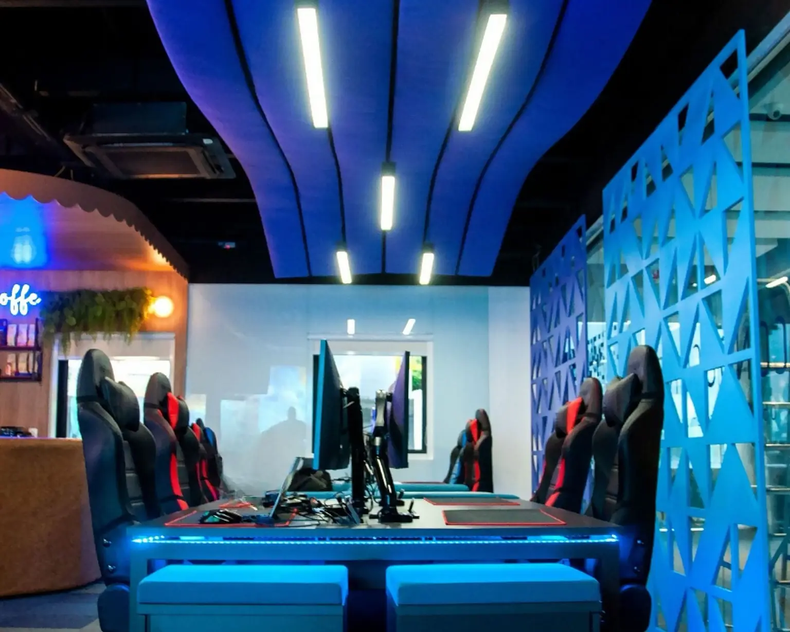 A Sala 09 da ACATE: a mesa de trabalho com o LED azul, a parede vazada em azul à direita e o neon do café ao fundo